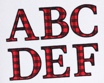 Pode incluir: Letras A, B, C, D, E e F em xadrez vermelho e preto, bordadas em um fundo branco.