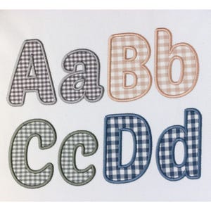 Può includere: Lettere ricamate A, a, B, b, C, c, D e d in un motivo a quadretti. Le lettere sono in vari colori, tra cui marrone, beige, verde e blu, con un bordo a contrasto. Le lettere sono su sfondo bianco.
