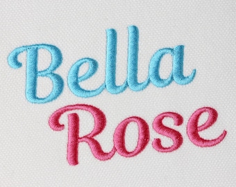 May include: The text Bella Rose is embroidered on a white fabric background. The word Bella is stitched in light blue thread using a cursive font, while the word Rose is stitched in bright pink thread using the same cursive font style.