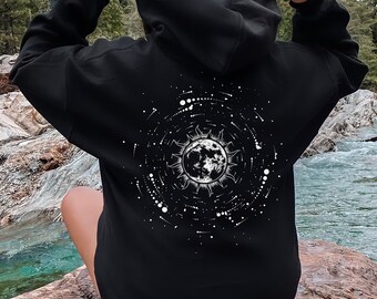 Peut inclure: Sweat-shirt à capuche noir avec un motif blanc d'un soleil et d'une lune entourés d'étoiles au dos.