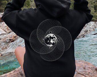 Peut inclure: Sweat à capuche noir avec un motif céleste blanc et gris au dos. Le motif représente une lune détaillée et des motifs tourbillonnants. La personne porte le capuchon, avec un arrière-plan panoramique d'une rivière et d'arbres.