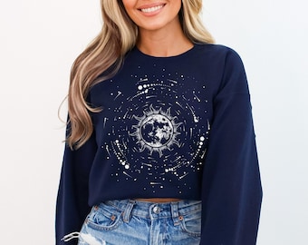 Peut inclure: Un sweat-shirt bleu marine court avec un motif blanc de lune et d'étoiles. Le sweat-shirt a des manches longues et une coupe décontractée.