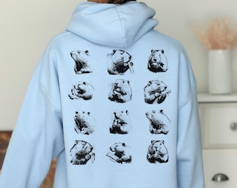 Peut inclure: Un sweat-shirt à capuche bleu clair avec un imprimé graphique de 16 images en noir et blanc de marmottes au dos.