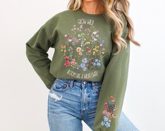 Peut inclure: Sweat-shirt vert avec un motif floral et le texte "Grow Wild, Bloom Like a Wildflower".