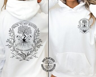 Peut inclure: Sweat-shirt à capuche blanc avec un motif noir et blanc d'un arbre avec des racines et le texte "Back to My Roots Apparel Company" au dos. Le devant du sweat-shirt présente une version plus petite du motif avec le texte "Back to My Roots Supports Reforestation".