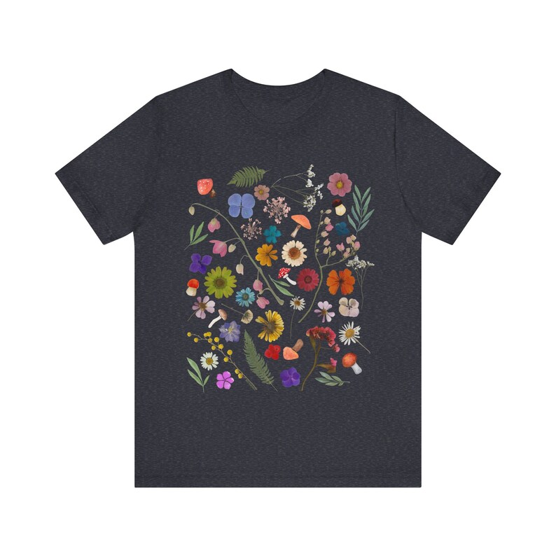 Może przedstawiać: Szary t-shirt w ciemnym odcieniu melanżu z kolorowym nadrukiem kwiatowym przedstawiającym r&oacute;żne kwiaty, liście i grzyby.