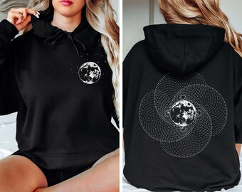 Peut inclure: Sweat-shirt à capuche noir avec un motif de lune et d'étoiles blanches sur le devant et un motif de lune blanche géométrique sur le dos.