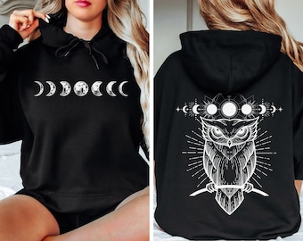 Peut inclure: Sweat-shirt à capuche noir avec un motif de phases de lune blanc sur le devant et un motif de hibou blanc avec des phases de lune au dos.