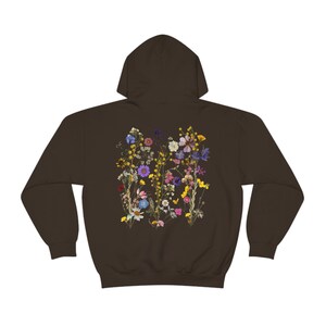 May include: A brown hooded sweatshirt with a floral print on the back. The print features a variety of dried flowers in shades of pink, purple, yellow, and blue.