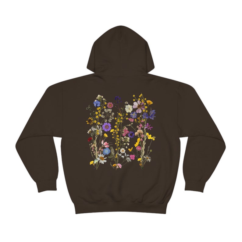 May include: A brown hooded sweatshirt with a floral print on the back. The print features a variety of dried flowers in shades of pink, purple, yellow, and blue.