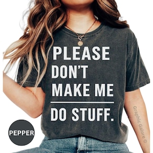 May include: Dark gray t-shirt with the text "PLEASE DON'T MAKE ME DO STUFF" in white block letters. The shirt has a crew neck and short sleeves. The word "PEPPER" is in a black circle in the lower left corner.