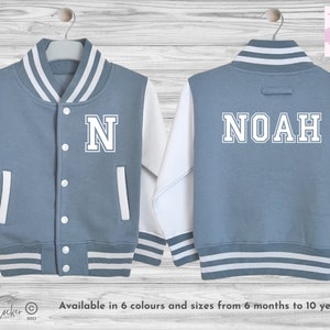 May include: A blue and white baseball style jacket with the name NOAH on the back and the letter N on the front. The jacket has white stripes on the sleeves and bottom.