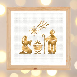 Può includere: Un ricamo a punto croce dorato della scena della Natività con una stella sopra la mangiatoia. La scena include Maria, Giuseppe e il bambino Gesù nella mangiatoia.