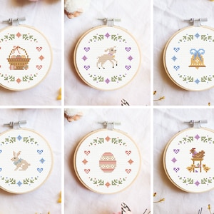 Puede incluir: Seis aros de bordado con diferentes diseños de temática de Pascua. Los diseños incluyen una cesta de huevos, un cordero, una campana, un conejito, un huevo y una gallina con pollitos.