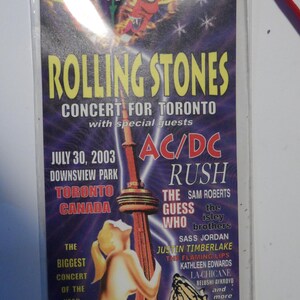 May include: A purple and blue concert ticket for the Rolling Stones concert in Toronto, Canada on July 30, 2003. The ticket features a graphic of the CN Tower and the text "Rolling Stones Concert for Toronto with special guests AC/DC, Rush, The Guess Who, Sam Roberts, The Isley Brothers, Sass Jordan, Justin Timberlake, The Flaming Lips, Kathleen Edwards, La-Chicane, Belushi-Aykroyd and more."