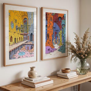May include: Two framed illustrations of colorful, abstract cityscapes. The illustrations are in a modern style and feature geometric shapes and patterns. The frames are wooden and have a natural finish.