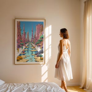 May include: A framed illustration of a futuristic city with tall buildings and a canal running through the centre. The city is painted in shades of pink, blue, and green. A woman in a white dress is standing in front of the artwork, looking at it.