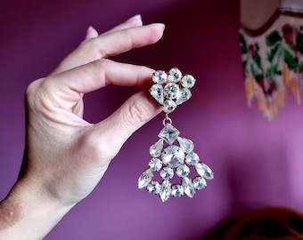 Opvallende vintage kroonluchterbroche met gefacetteerde, transparante strass-steentjes en goudkleurige accenten. Broche met kroonluchterstrass-steentjes, gouden kristallen en een juweel.