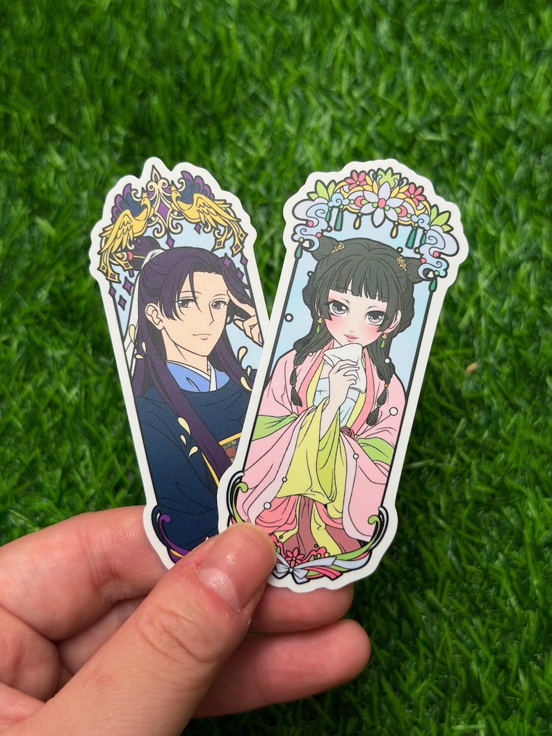 May include: Two stickers featuring anime-style illustrations of characters in traditional Asian attire. One sticker depicts a person in a blue and purple outfit, while the other shows a person in a pink and yellow outfit. Both stickers have decorative borders.