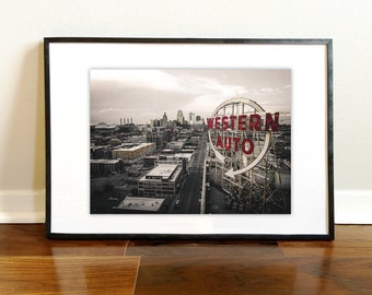 May include: A black and white aerial photograph of a city skyline with a large red sign that reads "WESTERN AUTO" in a circle.