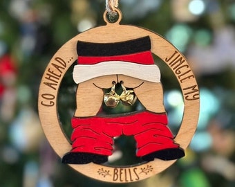 May include: A wooden Christmas ornament shaped like Santa Claus's backside with the text "Go Ahead... Jingle My Bells" and two gold jingle bells.