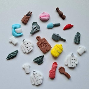 May include: A collection of 20 small, colourful, fondant cake toppers with a kitchen theme. The toppers include a chef's hat, a rolling pin, a whisk, a spatula, a cookie jar, a grater, a cutting board, a chef's jacket, a flour container, a pepper shaker, a red pepper, and a bag of chips.