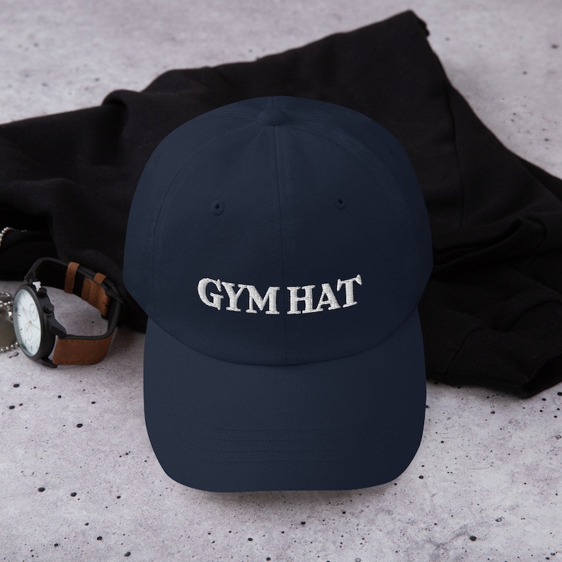 May include: A navy blue baseball cap with white embroidered text that reads "GYM HAT".