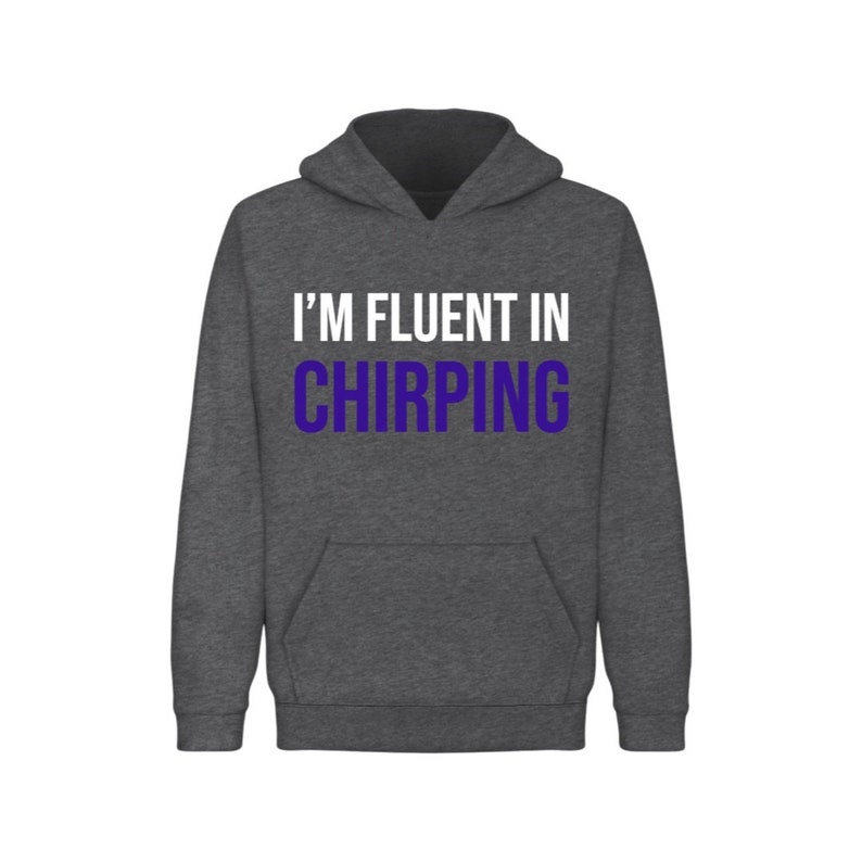 May include: A dark gray hooded sweatshirt with the text "I'M FLUENT IN CHIRPING" printed on the front. The text is in white with the word "CHIRPING" in purple.