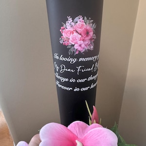 May include: A white ceramic mug with a black handle and the text "But First, Coffee" in a handwritten style. The mug is on a white surface. The mug is approximately 10 cm tall.
