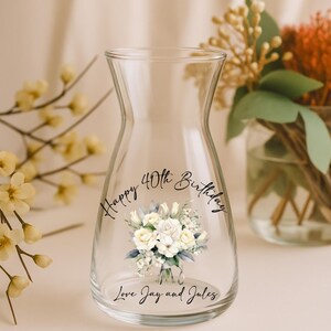 Pode incluir: Um vaso de vidro transparente com um design de buqu&ecirc; floral e o texto "Happy 40th Birthday, Love Jay and Jules." O vaso tem um formato &uacute;nico e &eacute; preenchido com flores.
