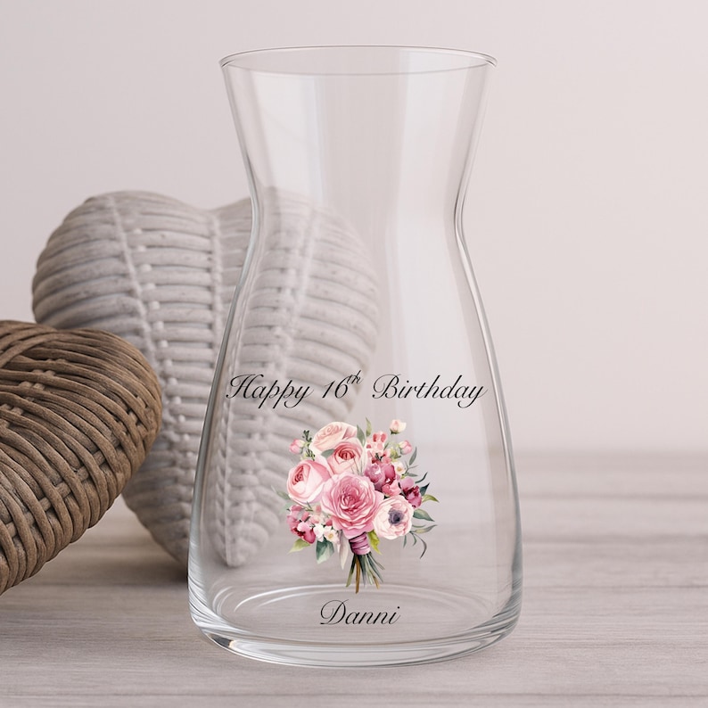 Pode incluir: Uma jarra de vidro transparente com uma base larga e um gargalo estreito. A jarra &eacute; decorada com um buqu&ecirc; floral em tons de rosa e roxo, e o texto "Happy 16th Birthday Danni".