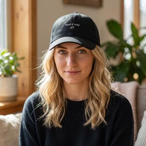 May include: A black baseball cap featuring the white embroidered text "bend & snap" centered on the front panel. The cap has a structured crown, a curved brim, and a button at the top center. The design is simple, clean, and features white stitching.
