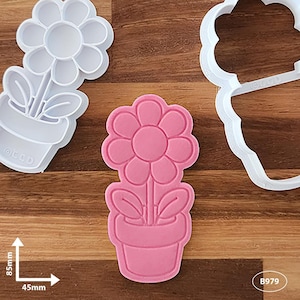 May include: A pink flower in a pot cookie cutter. The cutter is 4.5 inches wide and 8.5 inches tall. The cutter is made of white plastic.