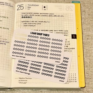 May include: Two sheets of white sticker paper with black outlines of stars and hearts. The top sheet has 40 small stars arranged in rows and the text "Mini Star Ratings" and "Little Bear Plans". The bottom sheet has 40 small hearts arranged in rows and the text "Mini Heart Ratings". Both sheets have a product code and a white background.