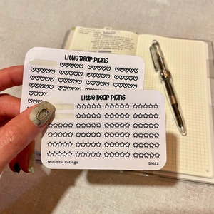 May include: Two sheets of white sticker paper with black outlines of hearts and stars. The top sheet has the text "Little Bear Plans" and the bottom sheet has the text "Little Bear Plans" and "Mini Star Ratings". The bottom sheet also has the text "S1022".