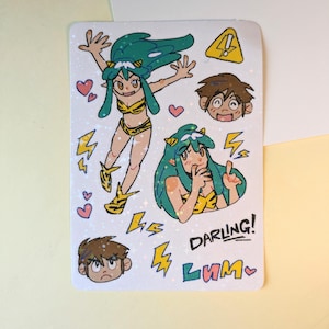 Puede incluir: Una hoja de pegatinas con ilustraciones de estilo anime. Muestra un personaje con cabello turquesa y un atuendo amarillo y negro, junto con otras cabezas de personajes, corazones y rayos. También están presentes las palabras "DARLING!" y "LUM".