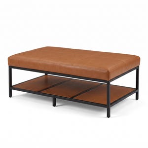 Peut inclure: Une table basse rectangulaire dotée d'un plateau en cuir beige capitonné et d'une étagère inférieure en cuir assorti. La structure est soutenue par un cadre en métal noir à quatre pieds, offrant un design épuré et fonctionnel pour tout intérieur.
