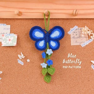 Puede incluir: Un adorno colgante de mariposa azul de ganchillo con un cuerpo azul oscuro y alas con detalles en azul claro. Debajo de la mariposa hay enredaderas de ganchillo verdes con pequeñas flores azul claro y hojas verdes. Texto: Blue Butterfly PDF PATTERN.