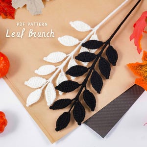 May include: A craft image features two crocheted leaf branches, one white and one black, with a brown background. The text "PDF PATTERN Leaf Branch" is visible. Decorative pumpkins and fall leaves in orange and red are also present.