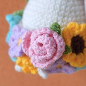 May include: A crocheted flower crown with pink, yellow, purple, and white flowers. The crown is made of yarn and is a handmade craft.