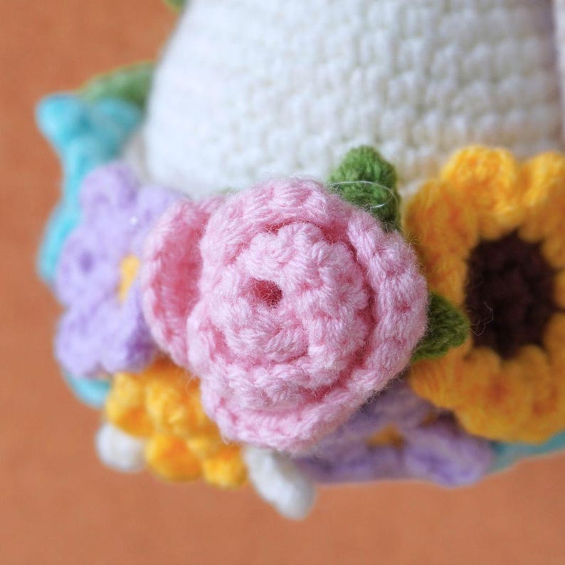 May include: A crocheted flower crown with pink, yellow, purple, and white flowers. The crown is made of yarn and is a handmade craft.