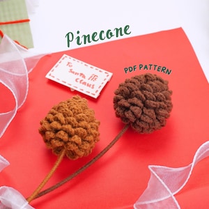Op de afbeelding: Twee bruine vilt dennenappels op een rode achtergrond met wit lint. De dennenappels zijn bevestigd aan bruine stelen. Een witte kaart met de tekst "To Santa Elf Claus!" is op de achtergrond. De tekst "Pinecone PDF Pattern" is in groene letters boven de dennenappels geschreven.