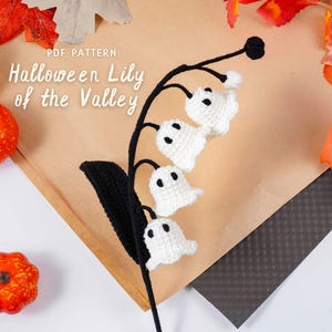 Może przedstawiać: Szydełkowa konwalia Halloween z białymi kwiatami w kształcie duchów oraz czarnymi łodygami i liśćmi. Widoczny tekst "PDF Pattern" i "Halloween Lily of the Valley". Dekoracyjne dynie i jesienne liście w tle.