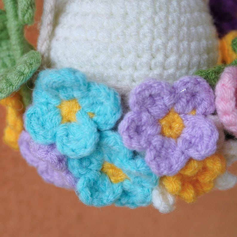 May include: A crocheted wreath with a white center and colorful flowers. The flowers are blue, purple, yellow, and pink.