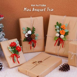 May include: Four rectangular gifts wrapped in brown paper and tied with twine, each adorned with a crocheted floral bouquet. The text PDF PATTERN Mini Bouquet Trio is centered above. A small Christmas tree with red ornaments is on the left.