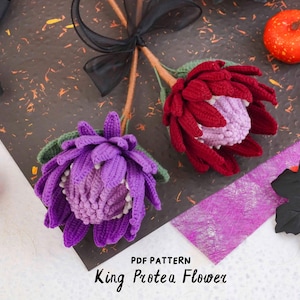 May include: Two crocheted King Protea flowers with long stems tied together by a black ribbon. One flower is deep purple with a light purple center, and the other is dark red with a pale pink center. Text reads: PDF PATTERN King Protea Flower.