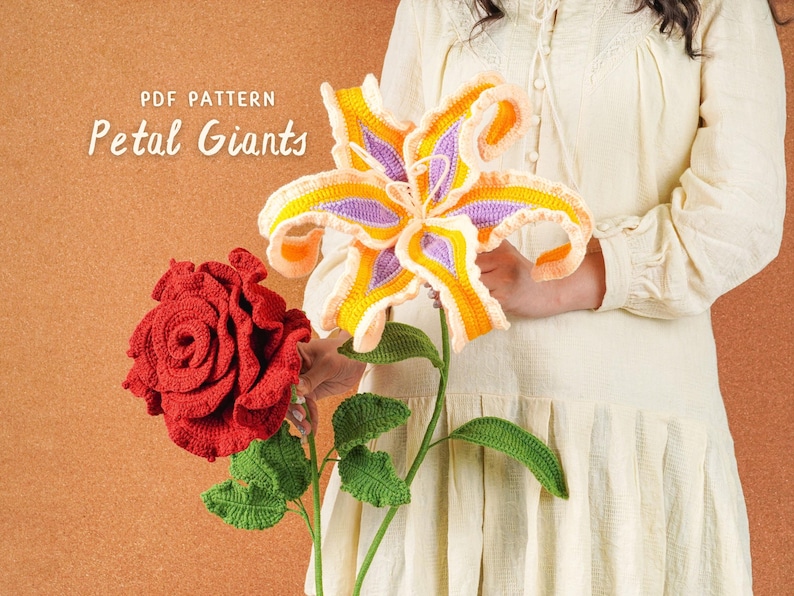 Op de afbeelding: Een persoon houdt twee grote, gehaakte bloemen vast: een rode roos en een gele, paarse en oranje lelie. De afbeelding bevat de tekst "PDF PATTERN Petal Giants" in witte letters.