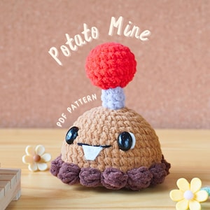 May include: A crocheted toy in the shape of a potato mine, with a brown body, a red top, and a white tooth. The text "Potato Mine" and "PDF PATTERN" are visible. The toy has black eyes and a purple stem.