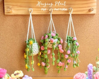 May include: Four crocheted hanging plant patterns with different colored flowers. The plants are hanging from a wooden board with the text "Hanging Plant PDF PATTERN" written on it.