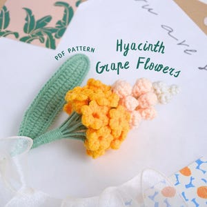 Puede incluir: Un ramo de flores de uva de jacinto de ganchillo con un tallo verde y flores de ganchillo amarillas, naranjas y blancas. El texto "PDF PATTERN" es visible en la esquina superior izquierda de la imagen. El texto "Hyacinth Grape Flowers" es visible en la parte superior central de la imagen.